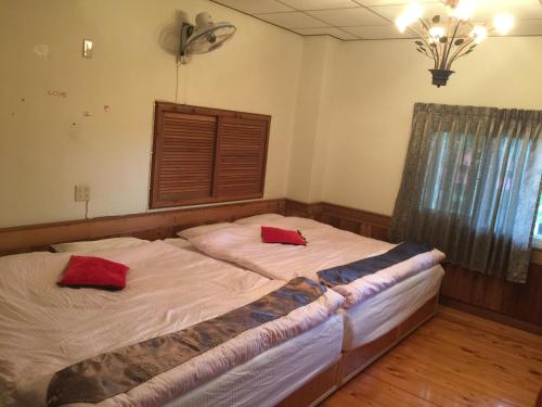 ein Schlafzimmer mit 2 Betten und roten Kissen darauf in der Unterkunft Shan Feng B&B in Gukeng