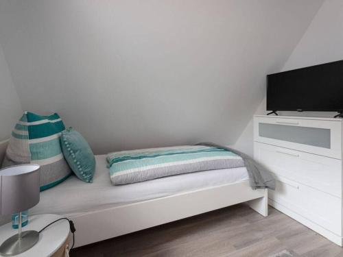 a white bedroom with a bed with pillows and a tv at Haus Sonneneck Comfortable holiday residence in Bad Arolsen