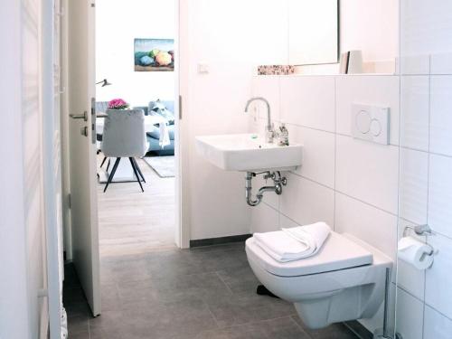 a white bathroom with a toilet and a sink at Old Printing House Holiday Apartment Gutenberg in Norderney