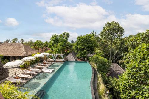 een overloopzwembad in een resort met stoelen en parasols bij The Sankara Suites and Villas by Pramana in Ubud