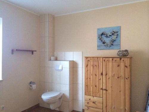 baño con aseo y una foto en la pared en Boddensurfer 2a Comfortable holiday residence, en Pruchten