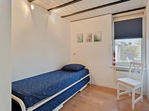Un dormitorio con una cama y una silla y una ventana. en Holiday home Huijsmansverhuur, en Ouddorp