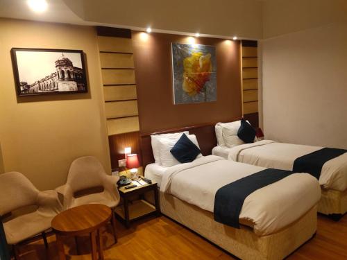 a hotel room with two beds and a table and chairs at Hotel the Plaza in Hyderabad