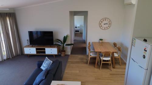 a living room with a table and a tv and a kitchen at BlueWater Apartments in Merimbula