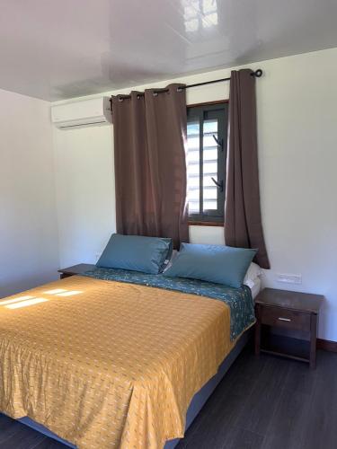 a bedroom with a bed with blue pillows and a window at Bungalow 2#FETI'A in Parea