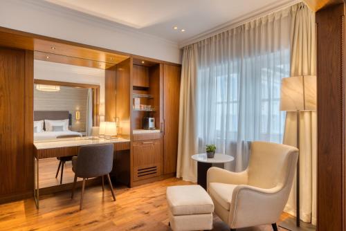 ein Hotelzimmer mit einem Bett, einem Schreibtisch und Stühlen in der Unterkunft Grand Hotel des Bains Kempinski in St. Moritz