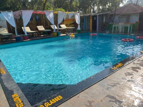 Art village resort Goa في محطة كاناكونا: مسبح ازرق كبير وفيه كراسي
