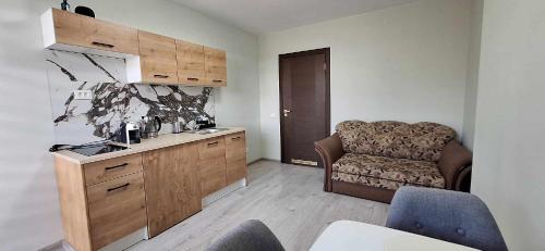 a kitchen with a couch and a chair in a room at Dainavos apartamentai Druskininkai in Druskininkai