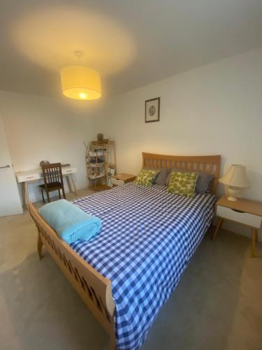 a bedroom with a bed with a blue and white checkered blanket at Torias Place - Lenham in Maidstone