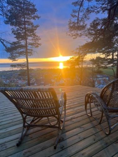 dos bancos sentados en una terraza de madera con la puesta de sol en Gränna Glamping, en Gränna