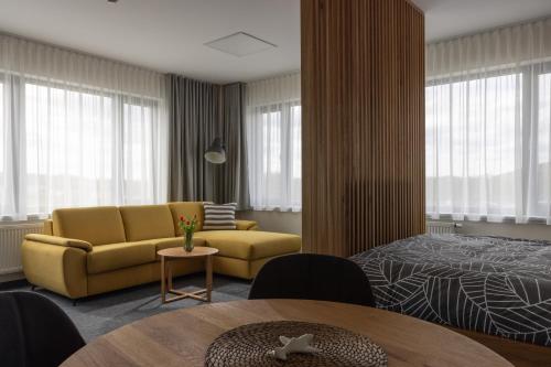a living room with a yellow couch and a bed at Apartmány Hangár Strakonice in Strakonice