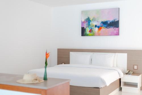 Un dormitorio con una cama y un jarrón con un sombrero en una mesa en Pinnacle Grand Jomtien Resort and Beach Club - SHA Extra Plus, en Na Jomtien