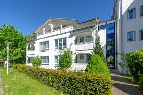 ein weißes Gebäude mit Büschen davor in der Unterkunft Haus Holstein - WG 6 mit Balkon, strandnah in Ostseebad Sellin