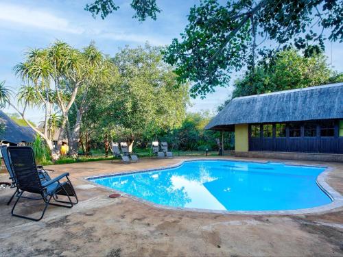 a swimming pool with a chair and a building at Kubu Safari Lodge in Hoedspruit