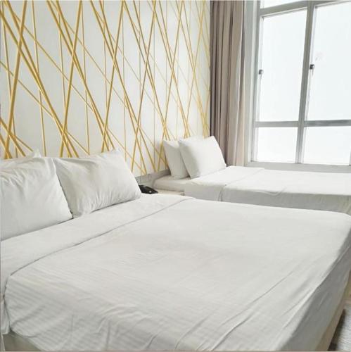 two white beds in a room with a window at Family room in Genting Highlands in Genting Highlands
