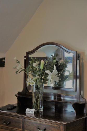 a vase of flowers on a dresser with a mirror at Star Inn Hotel in Upton upon Severn