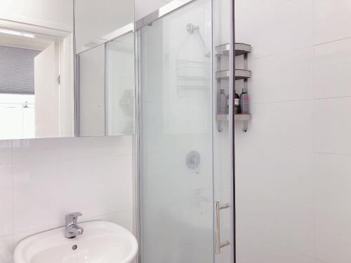 Un baño blanco con lavabo y ducha. en Serene Double Studio - Mins to Station & UNSW, en Sídney
