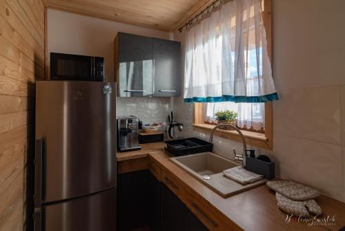 a kitchen with a stainless steel refrigerator and a sink at Domek u Hanci z balia na wyłączność in Ząb