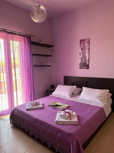 a bedroom with a purple bed with towels on it at Eva’s House in Vari
