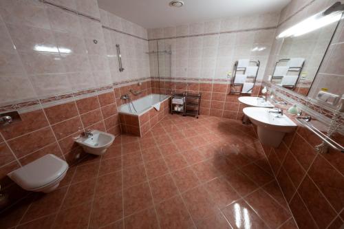 La salle de bains est pourvue de 2 toilettes, d'une baignoire et de lavabos. dans l'établissement IT Centrum Apartments, à Vrchlabí