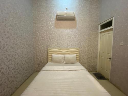 a small bedroom with a bed with a air conditioner on the wall at Griya RW Family Guest House Redpartner in Solo