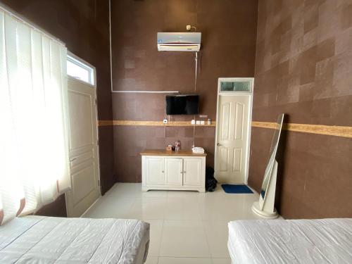 a room with two beds and a tv and a door at Griya RW Family Guest House Redpartner in Solo