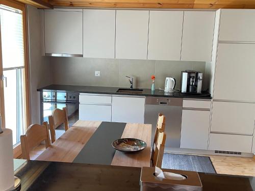 cocina con mesa de madera y armarios blancos en holiday home in M rel near the Aletsch ski area, en Mörel