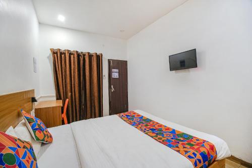 a bedroom with a bed and a tv on the wall at FabExpress Anurag Residency in Guwahati