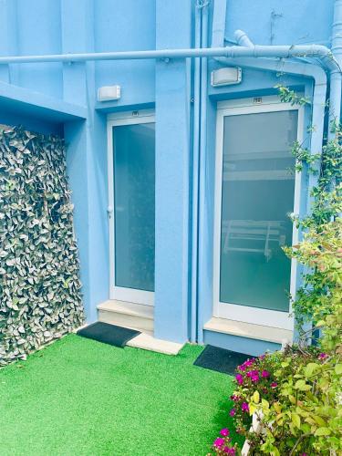 a blue building with two windows and green grass at Hotel Croce Del Sud in Rimini