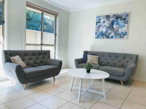 uma sala de estar com dois sofás e uma mesa em No Stairsducted Ac Near Cbd Richmond Sa em West Richmond