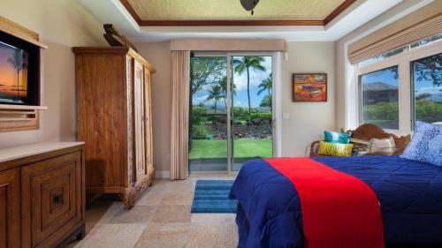een slaapkamer met een bed, een tv en een raam bij PLUMERIA HALE Exquisite 4BR KaMilo Home with Bikes and Beach Gear in Waikoloa