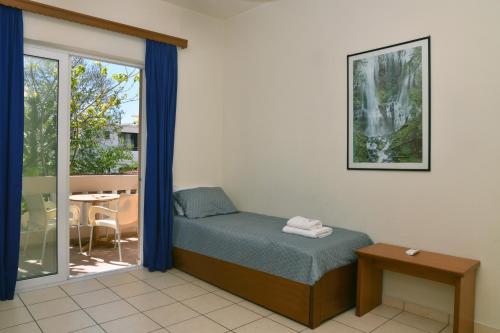 a bedroom with a bed and a balcony with a table at Akatos Hotel in Agia Marina Nea Kydonias