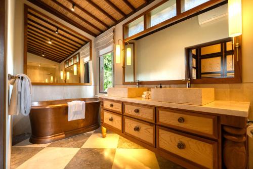 une salle de bains avec baignoire et lavabo dans l'établissement The Ubāri Bali - Luxury Riverside Escape, à Ubud