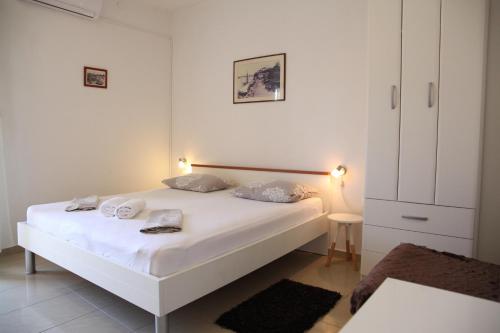 a bedroom with a white bed and a white cabinet at Apartments Kresan in Zadar