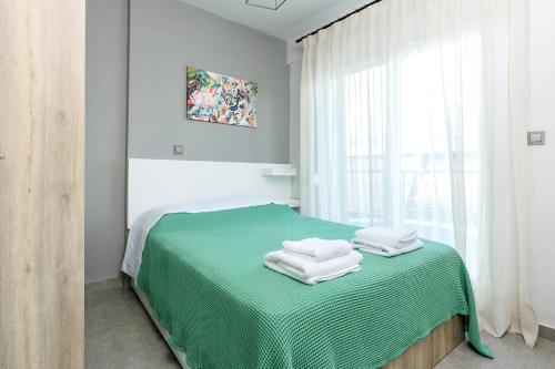 ein Schlafzimmer mit einem grünen Bett und Handtüchern darauf in der Unterkunft FAOS Properties in Kavala
