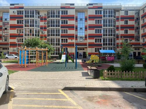 un parco giochi vuoto di fronte a un grande edificio di Думан-2 a Almaty