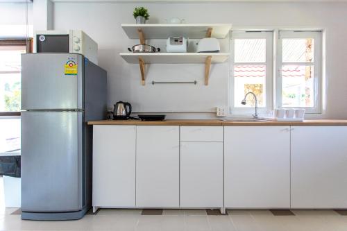 eine Küche mit weißen Schränken und einem Kühlschrank in der Unterkunft F4 Beach house Kitchen BBQ 3 bedrooms Large yard in Rayong