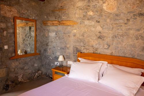 a bedroom with a bed and a stone wall at Pappou's Traditional Cottage at Epano Elounda in Elounda