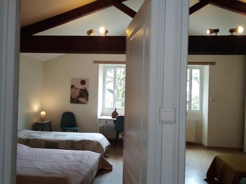 um quarto com 2 camas, uma secretária e 2 janelas em Les Trois Geais em Les Épesses
