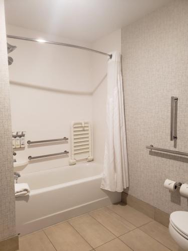 a bathroom with a white tub and a toilet at Holiday Inn Express & Suites Kingsland I-95-Naval Base Area by IHG in Kingsland