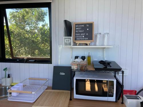 Kuchnia z oknem i blatem z kuchenką mikrofalową w obiekcie Sweet Retreat w mieście Bundaberg