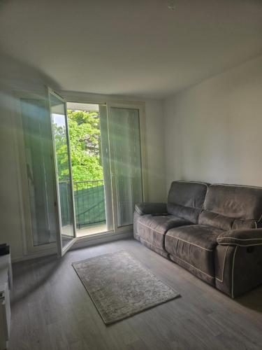 un salon avec un canapé et une grande fenêtre dans l'établissement Appartement T3 tout confort, à Sartrouville