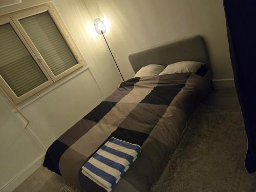 un lit dans une chambre avec une lampe à côté d'une fenêtre dans l'établissement Appartement T3 tout confort, à Sartrouville