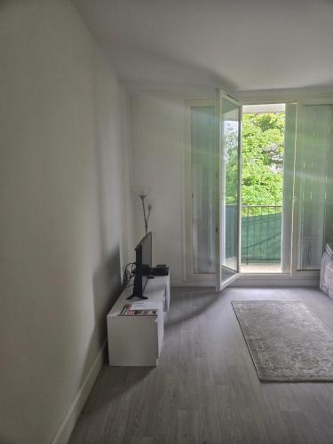 un salon avec une télévision et une grande fenêtre dans l'établissement Appartement T3 tout confort, à Sartrouville