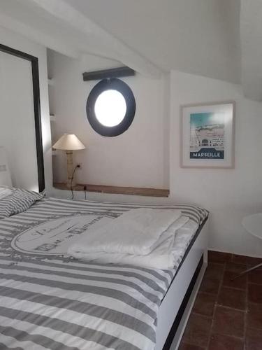 a bedroom with a bed with a round window on the wall at STUDIO PORT MIOU terrasse proximité mer - Calanques in Marseille
