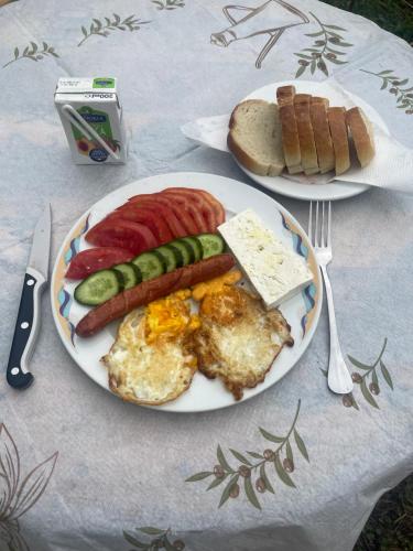 a plate of breakfast food with eggs sausage and bread at Lake Campground Silvano in Berat