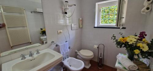 uma casa de banho com um lavatório, um WC e um vaso de flores em Hotel La Giada del Mesco em Levanto