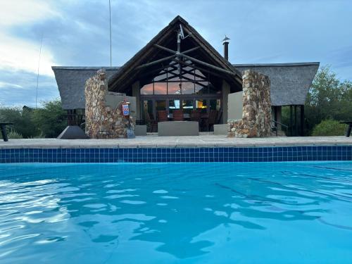 ein Haus mit einem Pool vor einem Gebäude in der Unterkunft Morokolo Safari Lodge Self-catering in Pilanesberg
