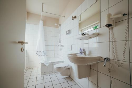 a white bathroom with a toilet and a sink at guestified LIYANA in Ratingen