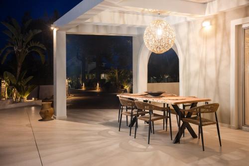 a dining room table with chairs and a chandelier at Porta Verde Luxury Residence, By TK Property Management in Laganas